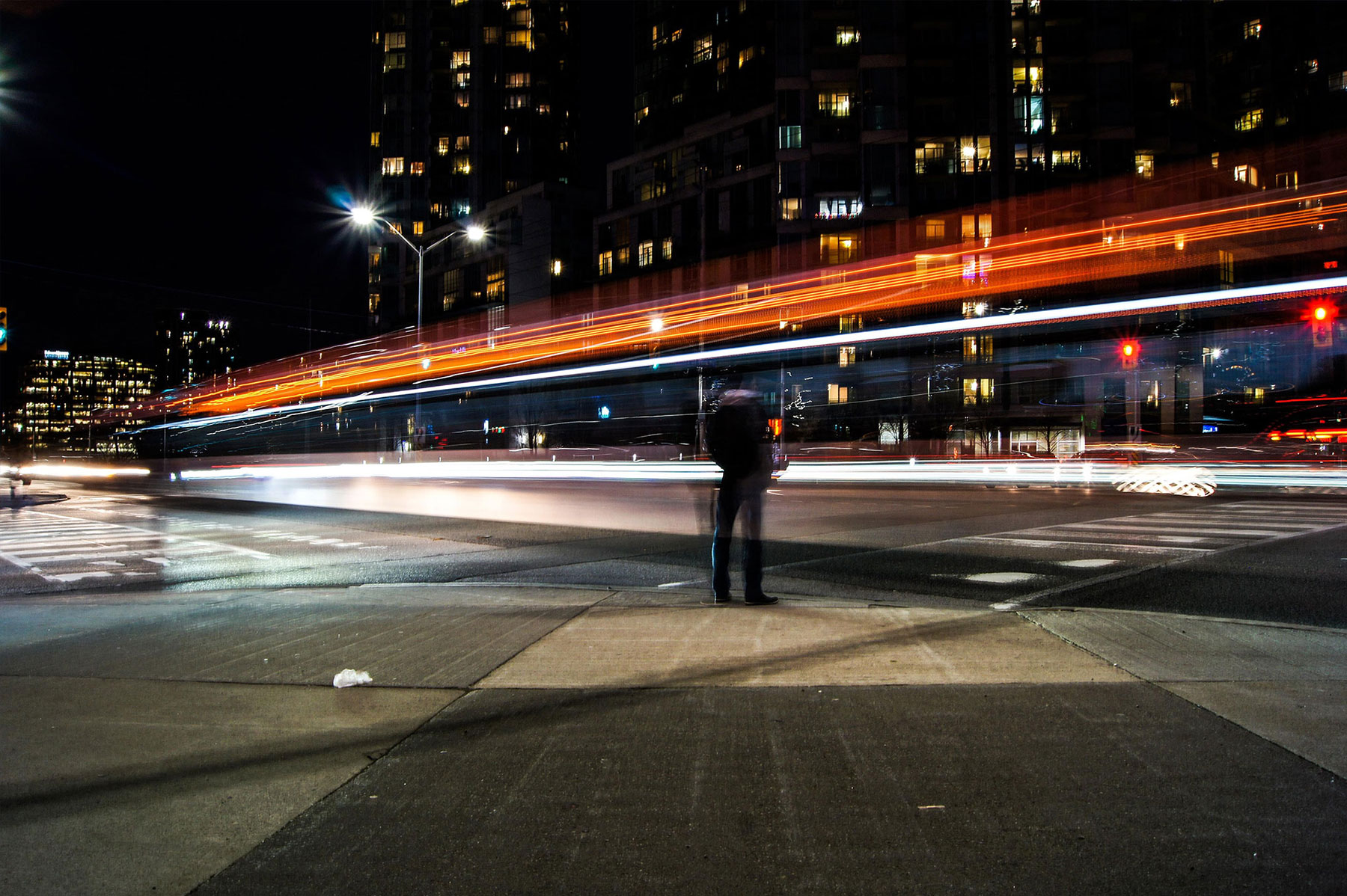 Timelapse of cars speeding by pedestrian on city street