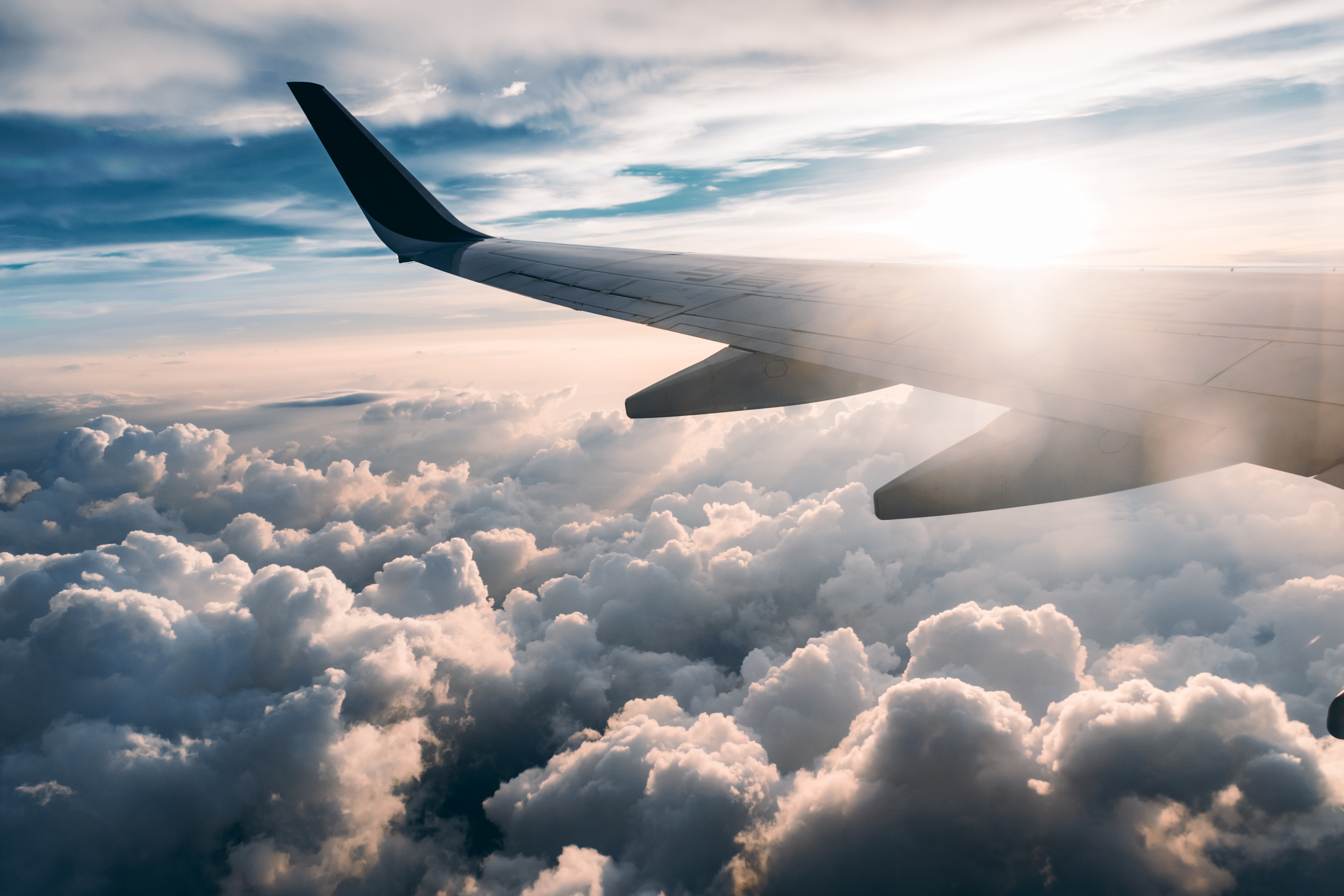 Airplane wing in sky over clouds