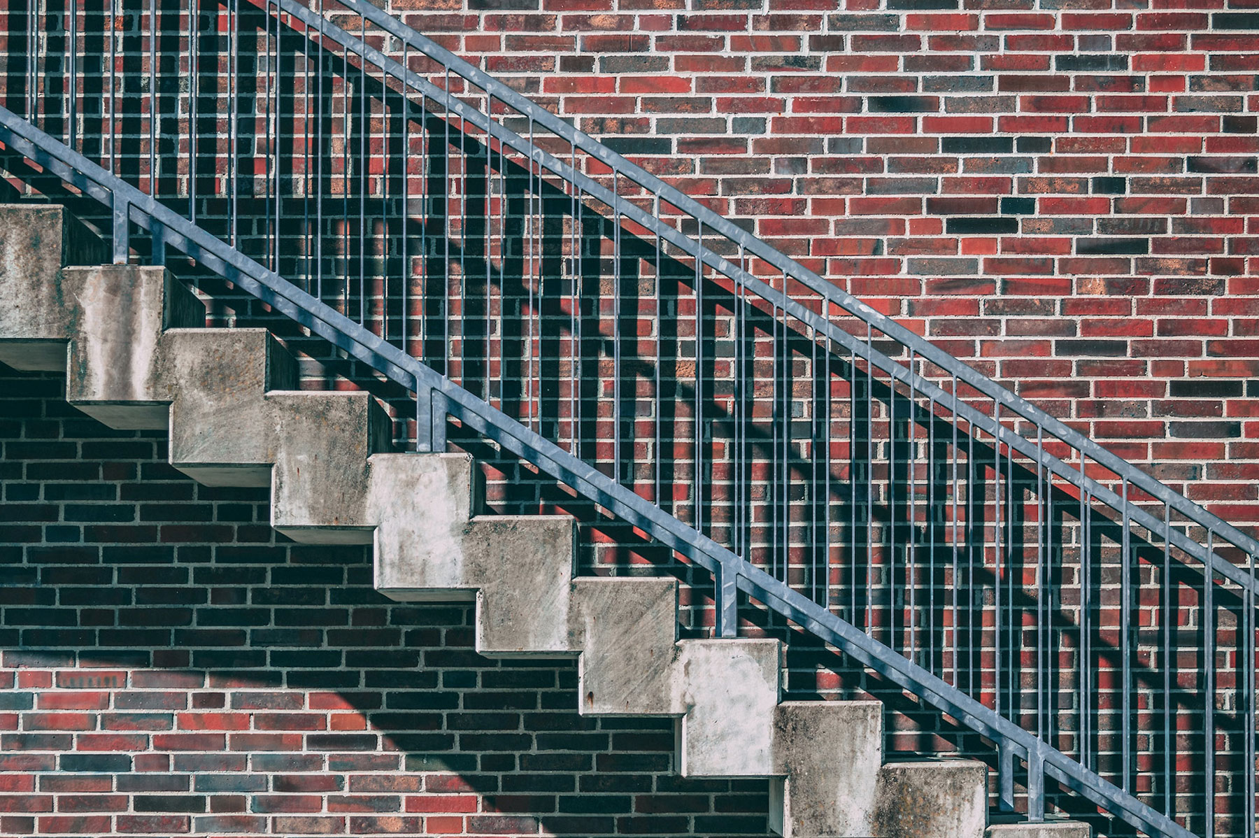 gray metal ladder next to red brick wall